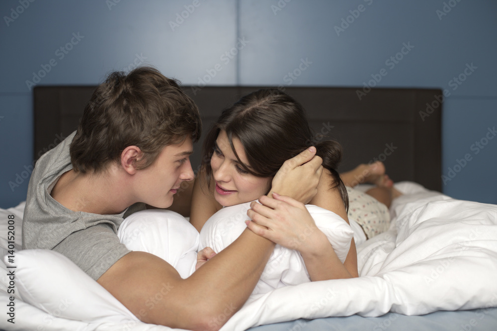 Young couple lying on front in bed, selective focus Young couple lying on front in bed, selective focus