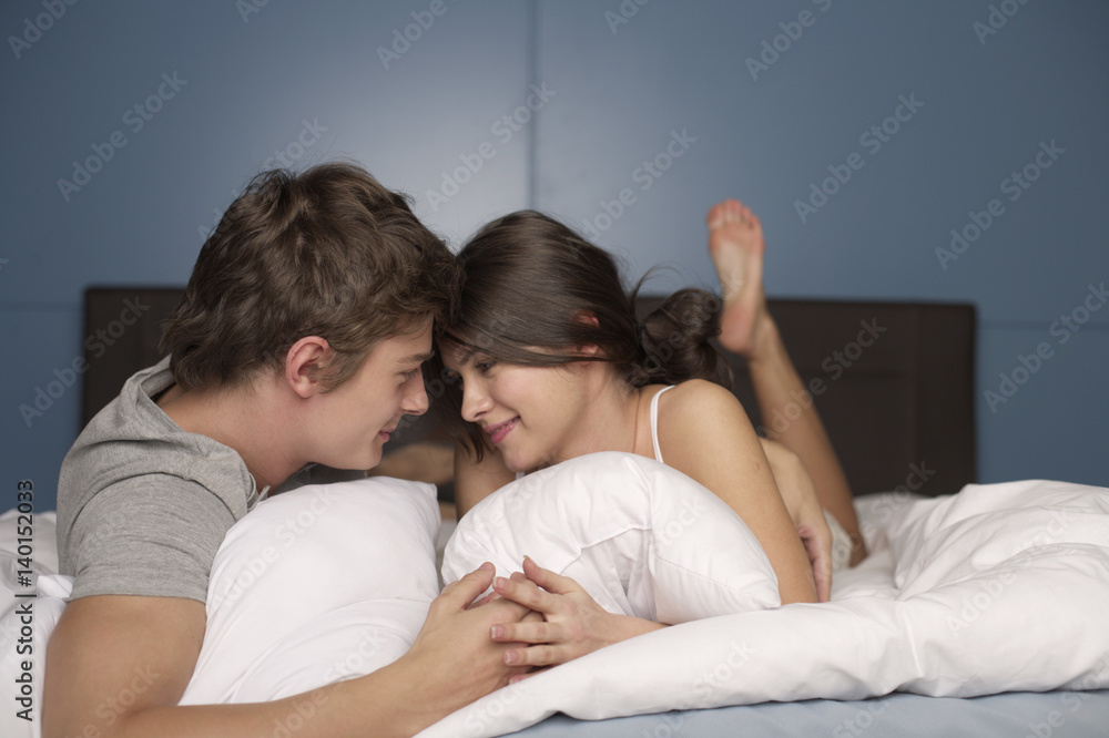 Young couple lying on front in bed, selective focus Young couple lying on front in bed, selective focus