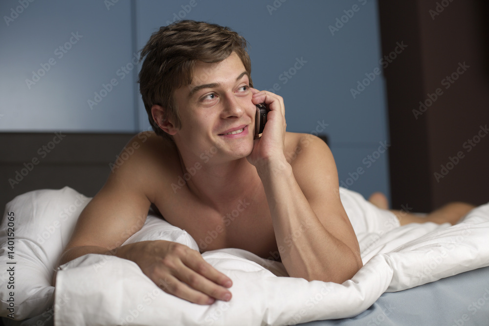 Young naked man in bed while phoning, close-up, portrait Young naked man in bed while phoning, close-up, portrait