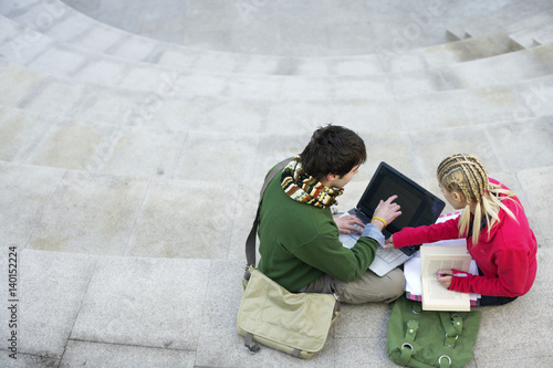 Young couple using a laptop on a staircase