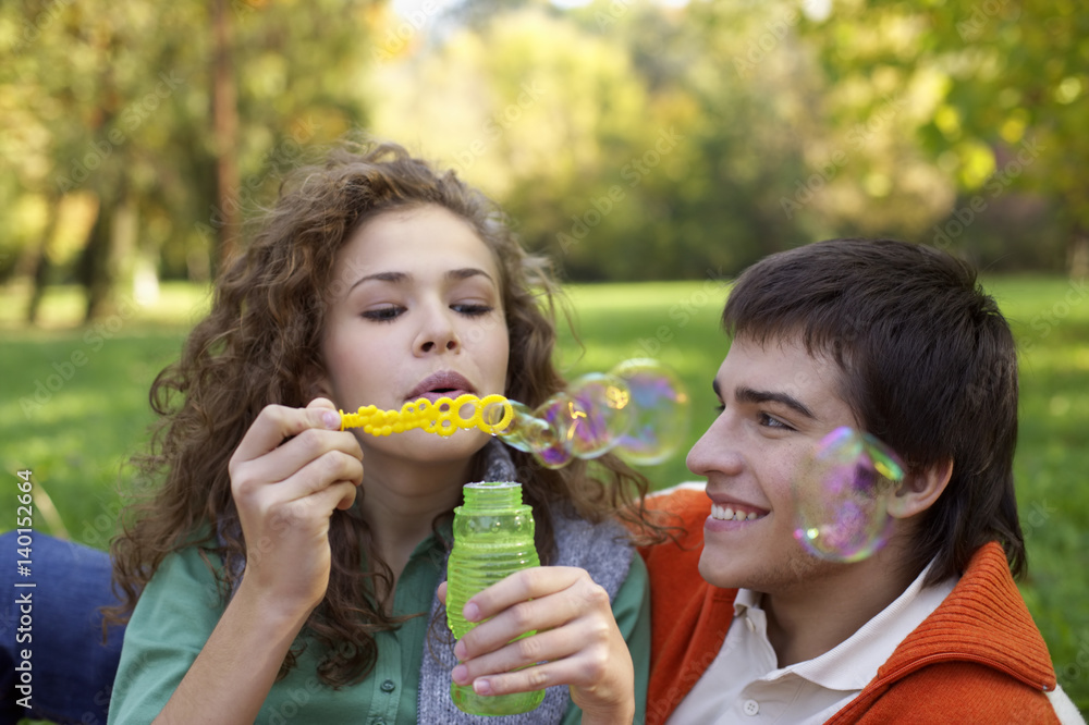Teenage boy and girl making soap bubbles, close-up, selective focus Teenage boy and girl making soap bubbles, close-up, selective focus