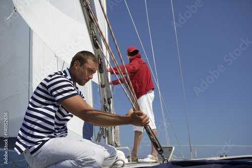 Two men working on a sailing yacht