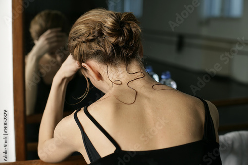 Exhausted female ballet dancer sitting in front of a mirror