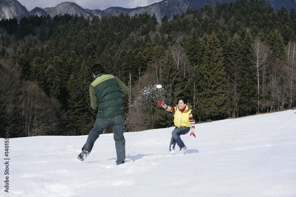 Young couple having a snowball fight