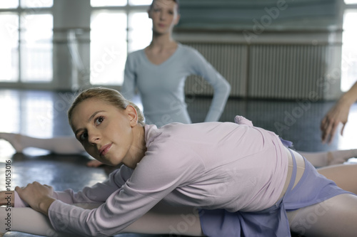Female ballet dancers doing stretching exercises on the floor
