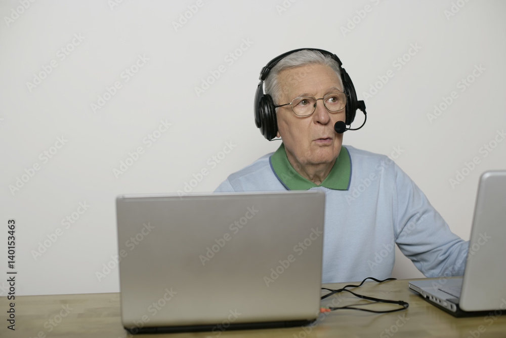 Senior man with headset using a laptop, fully_released Senior man with headset using a laptop, fully_released