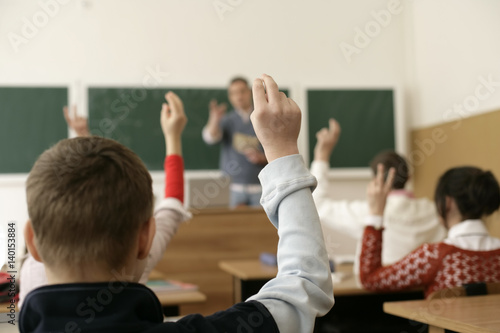 View inside a classroom, pupils raising arms