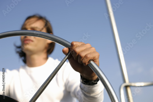 Man at the steering wheel of a sailboat
