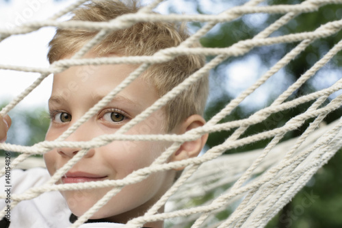 Boy looking through mesh of a hammock