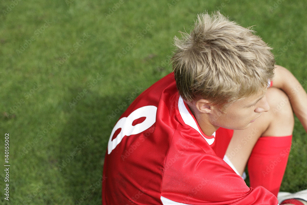 Naklejka premium Soccer player sitting on grass