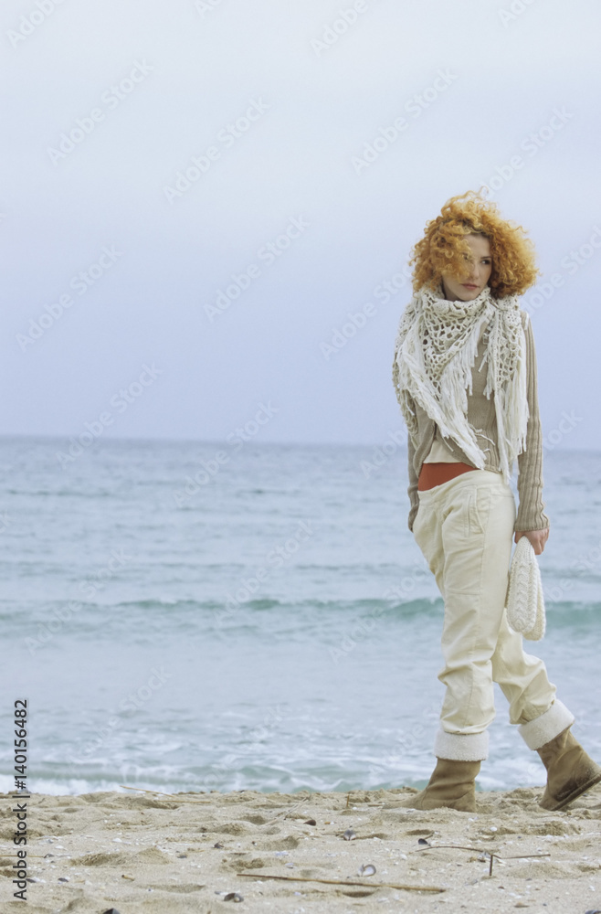Woman with a strawberry blonde curly Head strolling along the Beach - Lonliness - Season - Nature