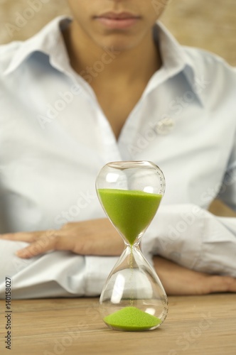 Woman looking at hourglass with green sand