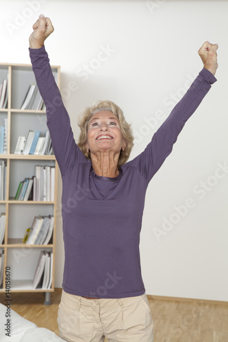 Senior woman cheering with arms raised