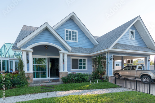 Bright blue house in sunlght with colorful poppies and some graceful trees