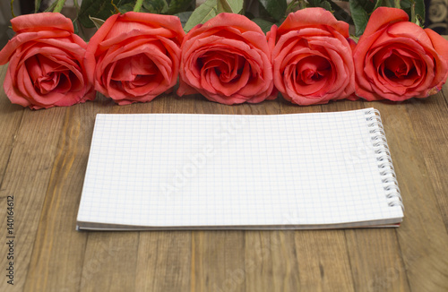 bouquet red pose flowers and paper notebook