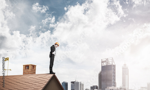 Businessman looking down from roof and modern cityscape at backg