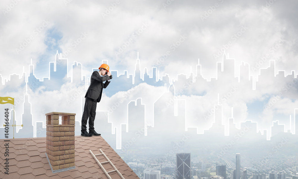 Engineer man standing on roof and looking in binoculars. Mixed media Engineer man standing on roof and looking in binoculars. Mixed media