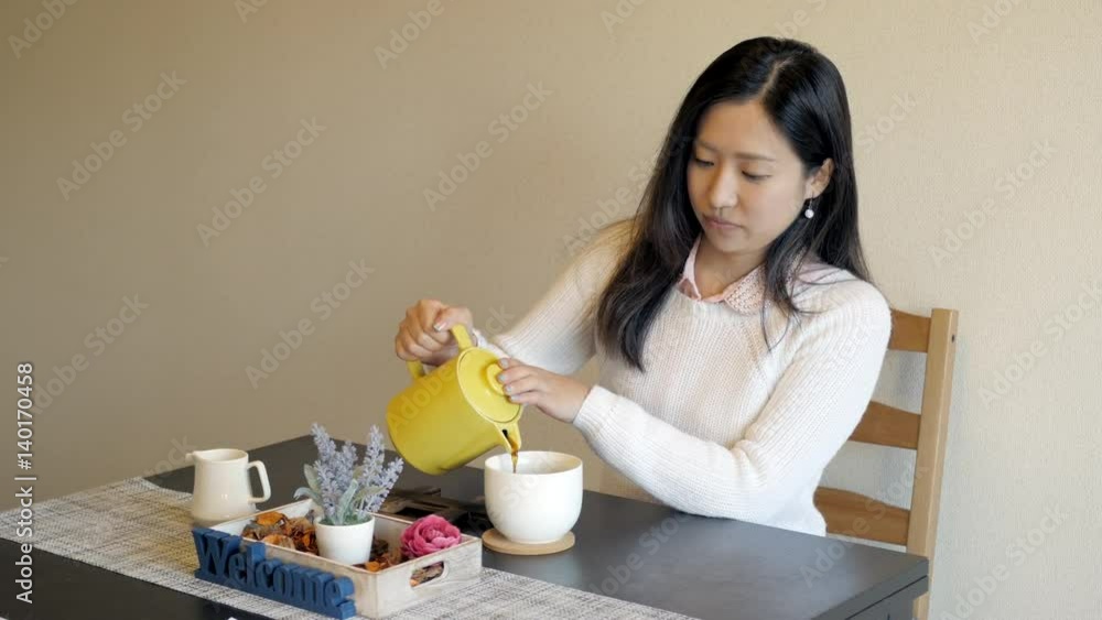 Cute Japanese girl pouring some coffee and relaxing in a small cafe. Cute Japanese girl pouring some coffee and relaxing in a small cafe.