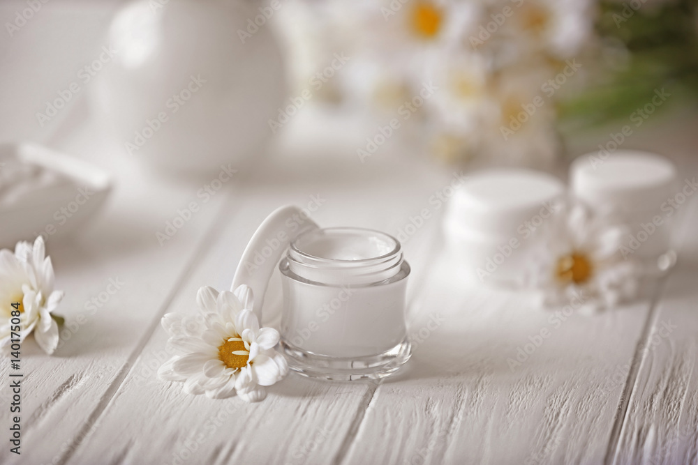 Spa concept. Nourishing cream and daisy flowers on white wooden table