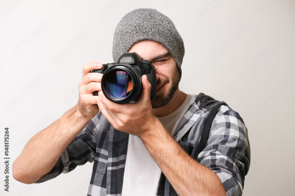 Handsome young photographer on light background