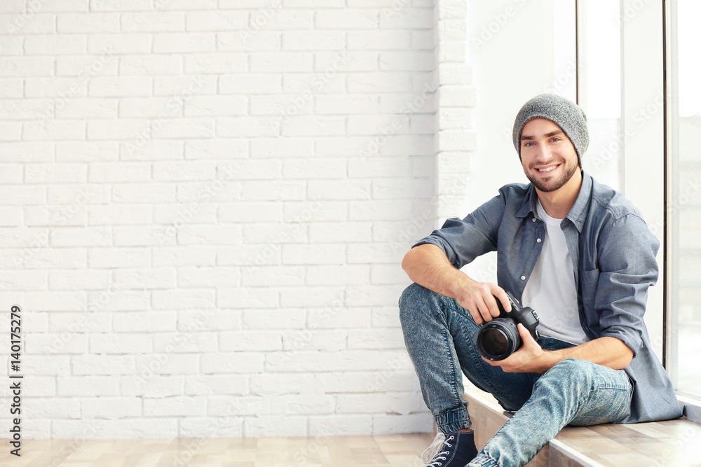 Handsome young photographer sitting on window sill