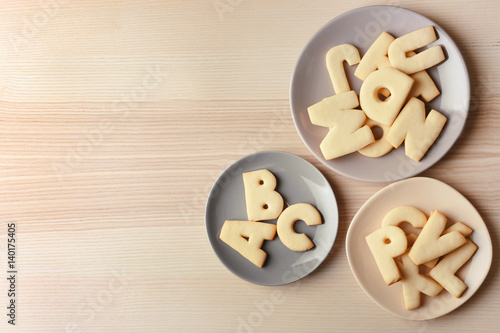 Plates with cookie alphabet on wooden  table