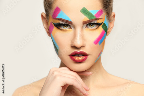 Face of beautiful young woman with creative make up on light background