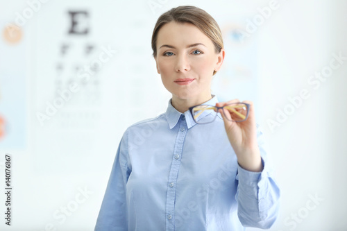 Woman holding eyeglasses in...