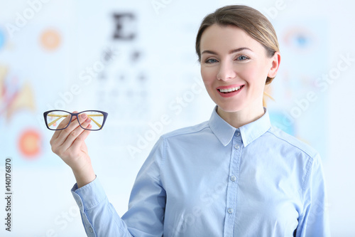 Woman holding eyeglasses in...