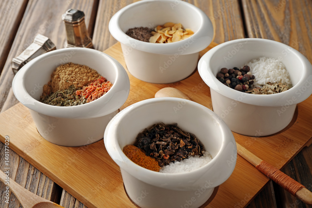 Bowls with different spices on wooden board Bowls with different spices on wooden board