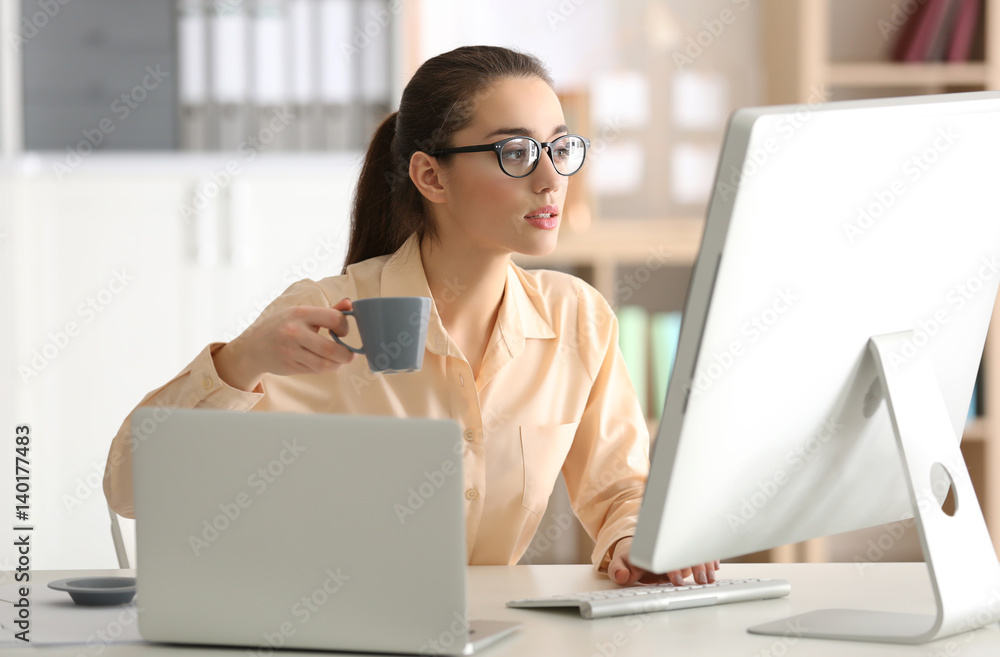 Young woman working and drinking coffee at office Young woman working and drinking coffee at office