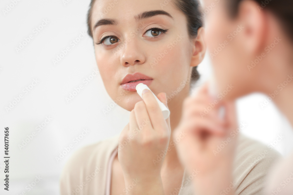 Woman applying hygienic lip balm near mirror Woman applying hygienic lip balm near mirror
