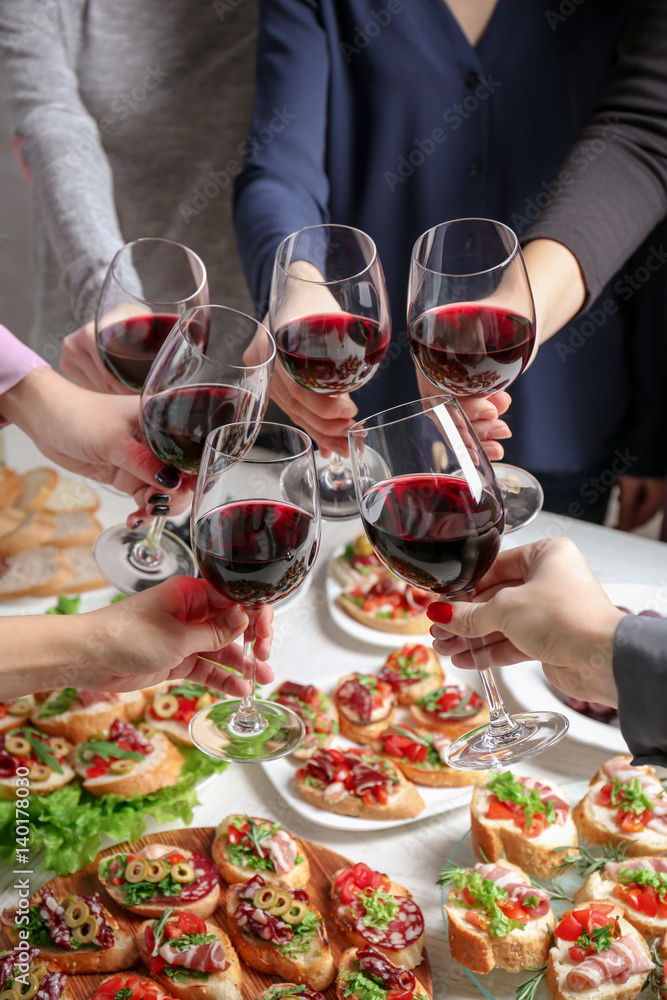 People clinking glasses with wine and delicious dishes on table
