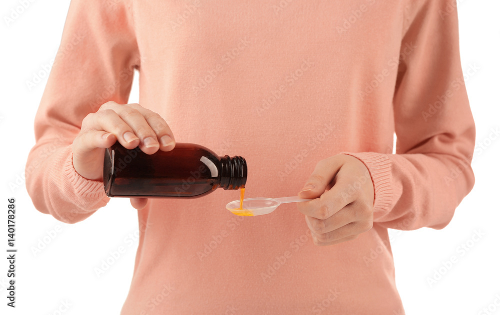Fototapeta premium Woman pouring cough medicine syrup into spoon on white background