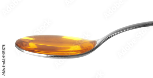 Yellow cough medicine syrup in silver spoon isolated on white