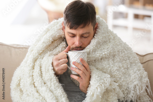 Young ill man drinking hot ...