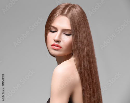 Attractive young woman with beautiful long hair on light background