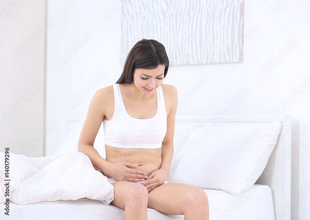 Beautiful pregnant woman suffering from stomach ache sitting on bed Beautiful pregnant woman suffering from stomach ache sitting on bed