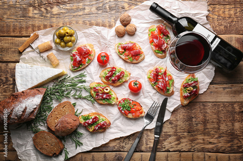 Fototapeta Tasty bruschetta served with wine on wooden background