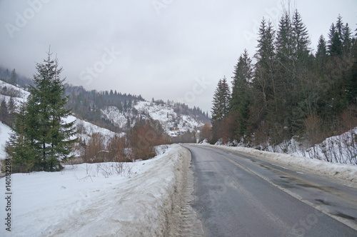 A long road stretches between the snow-capped mountains