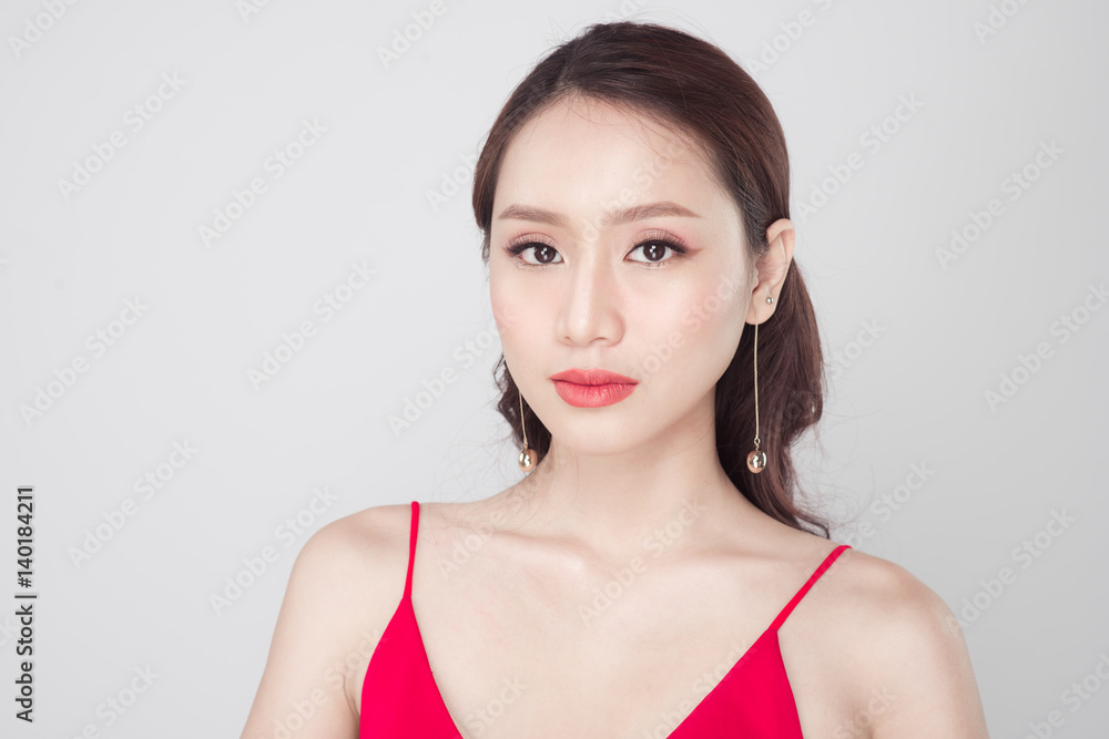 Beautiful stylish asian woman wearing red dress on grey background. Beautiful stylish asian woman wearing red dress on grey background.
