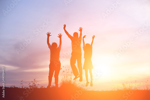 Silhouette group of friends having fun jumps on sunset and mountains backdrop 
