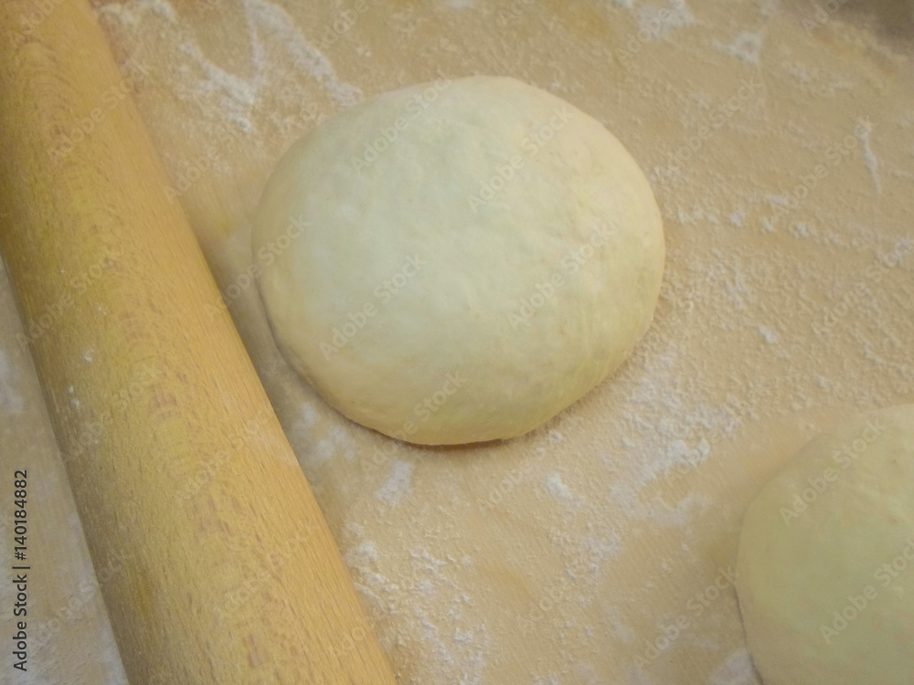 dough and flour on a wooden board, a rolling pin and a towel dough and flour on a wooden board, a rolling pin and a towel