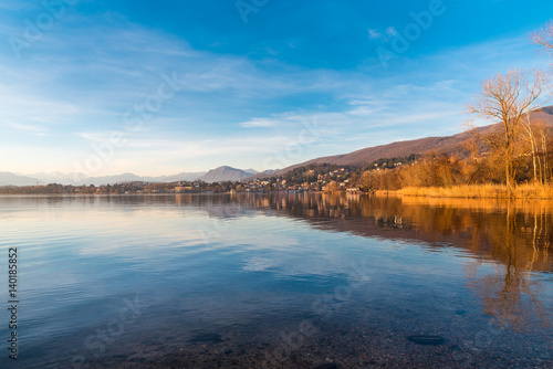 Lake Varese  Gavirate. Italy. Landscape toward the small tourist resort of Gavirate in the province of Varese  on a beautiful day with blue sky and white clouds. On the background the Alps