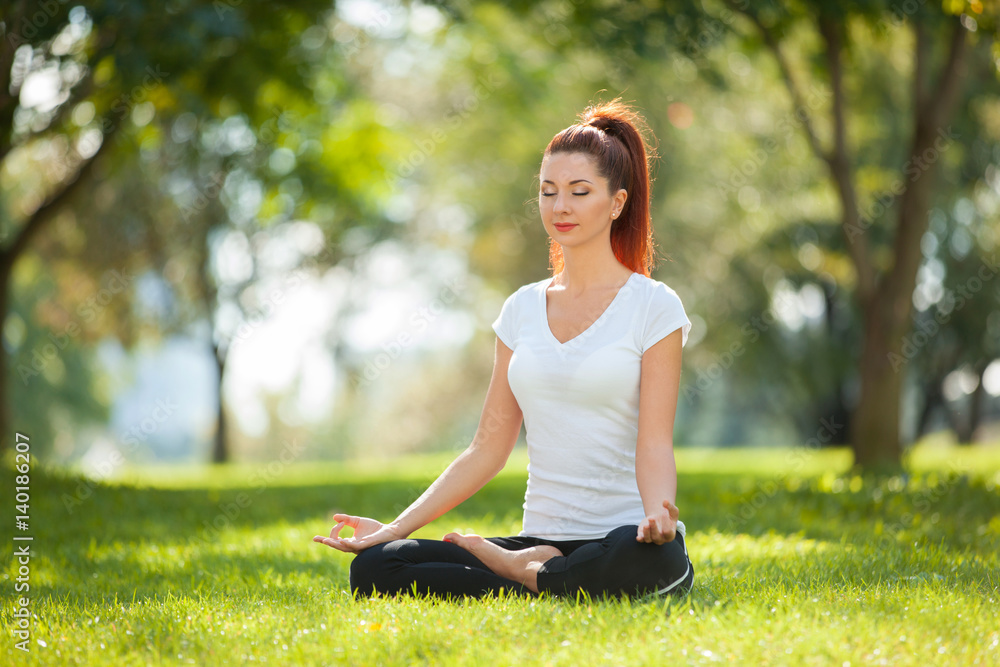 Yoga outdoor. Happy woman doing yoga exercises, meditate in the park. Yoga meditation in nature. Concept of healthy lifestyle and relaxation. Pretty woman practicing yoga on the grass Yoga outdoor. Happy woman doing yoga exercises, meditate in the park. Yoga meditation in nature. Concept of healthy lifestyle and relaxation. Pretty woman practicing yoga on the grass