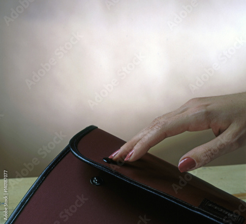 close-up of a hand closing a suitcase or briefcase photo