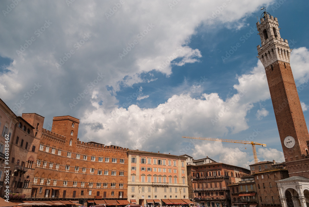 Tower of Mangia, piazza del Campo, Sienna, Italy, with nearby buildings and dramatic sky