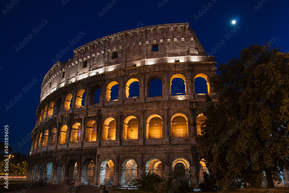 Colosseum in Rome, Italy, illuminated at night with moon shining above
