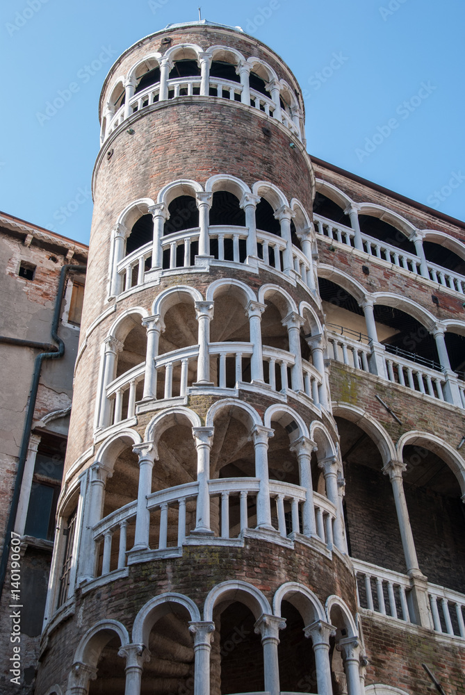 Ancient cylindrical staircase stone tower, Venice, Italy with white arches and pillars