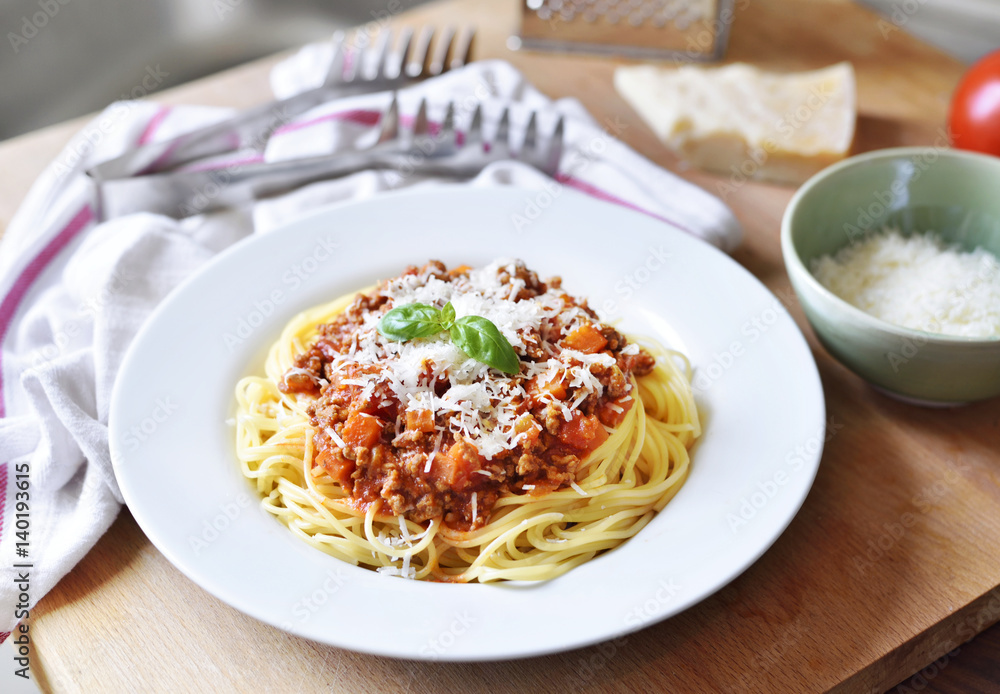 Spaghetti Bolognese on a white plate with decorative basil leaf. Italian cuisine, pasta with tomato sauce and parmesan cheese. Spaghetti Bolognese on a white plate with decorative basil leaf. Italian cuisine, pasta with tomato sauce and parmesan cheese.